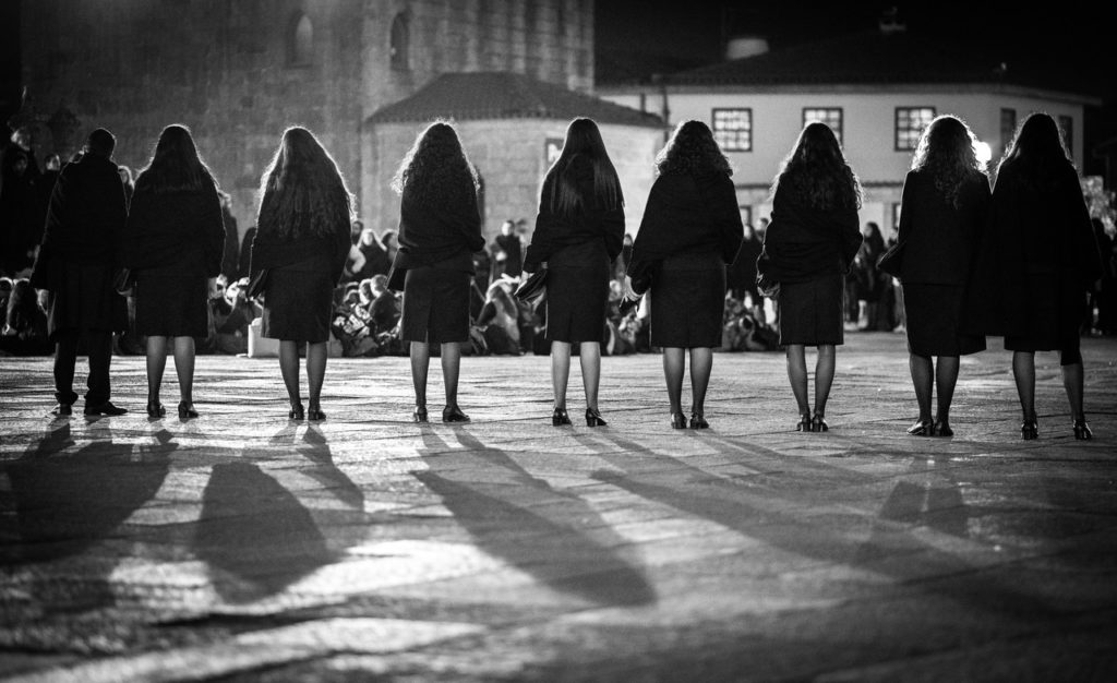 A line of performers seen from behind in a square at night